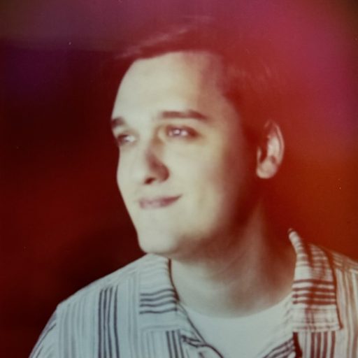 A side profile of a man smiling with a red background.